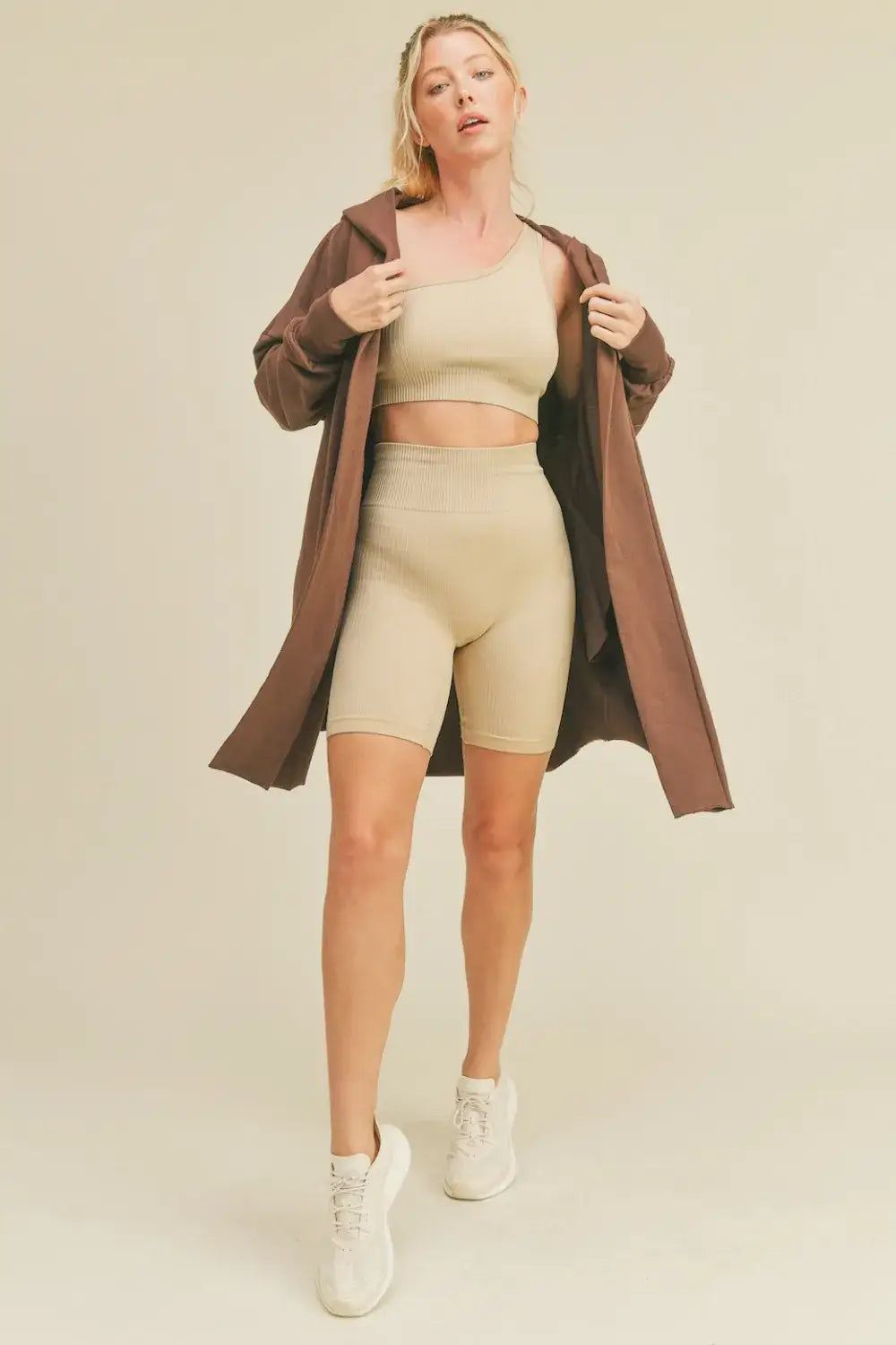 Beige cycling shorts with matching crop top, white sneakers, and Kimberly C Open longline hooded cardigan