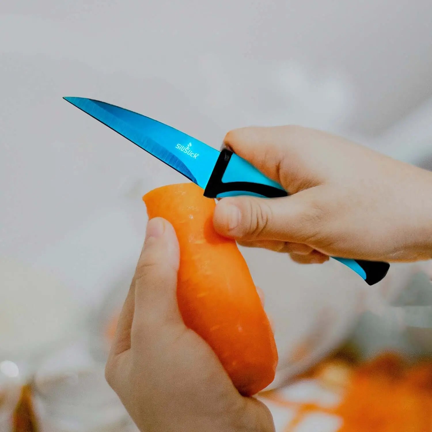 Vibrant blue kitchen knife from knife set kit peeling a carrot in a modern kitchen