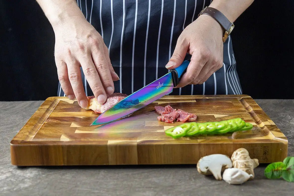 Rainbow-colored chef’s knife from Kitchen Knife Set Kit slicing meat on wooden board