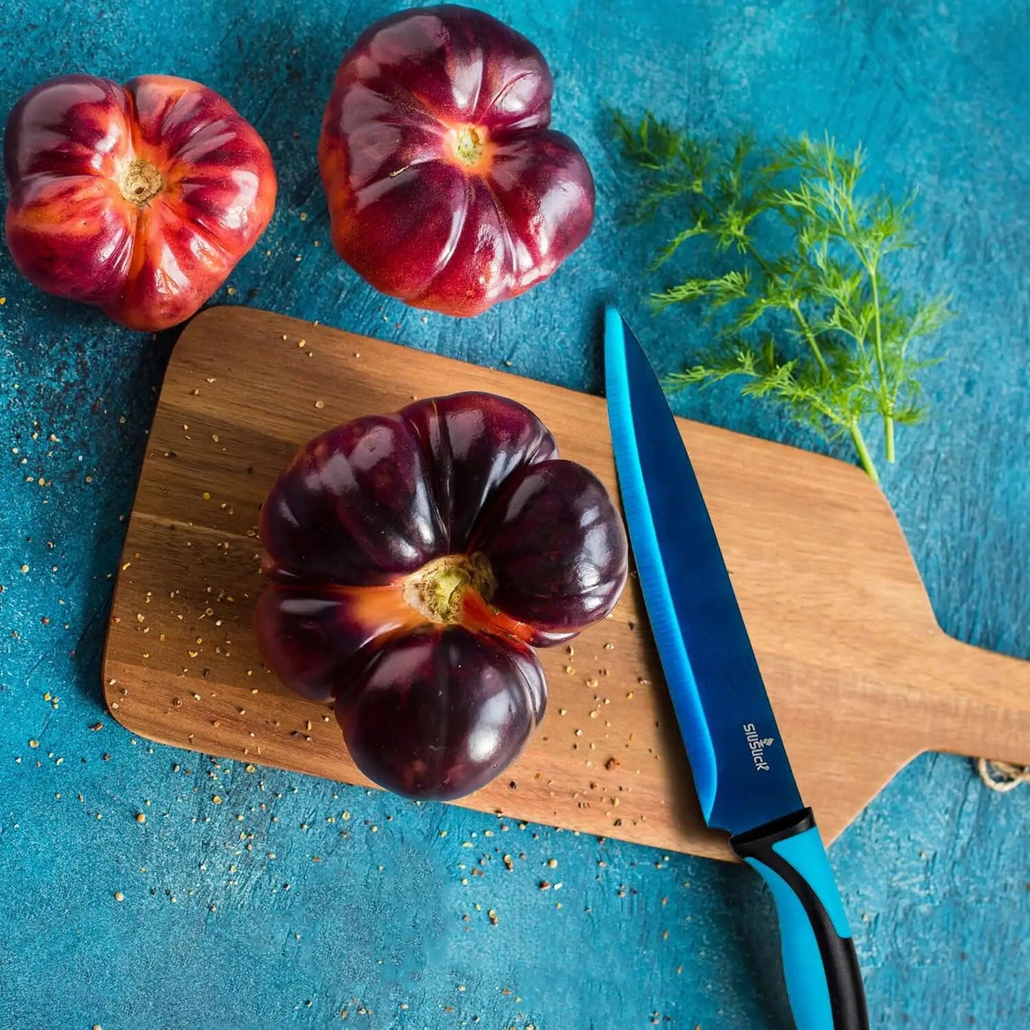 Vibrant ribbed tomatoes with deep purple and red hues next to a kitchen knife in a knife set