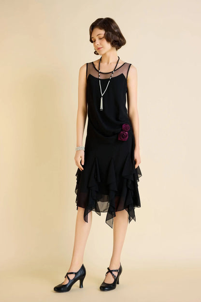 Woman modeling a black Gatsby floral ruffled day dress with sheer neckline