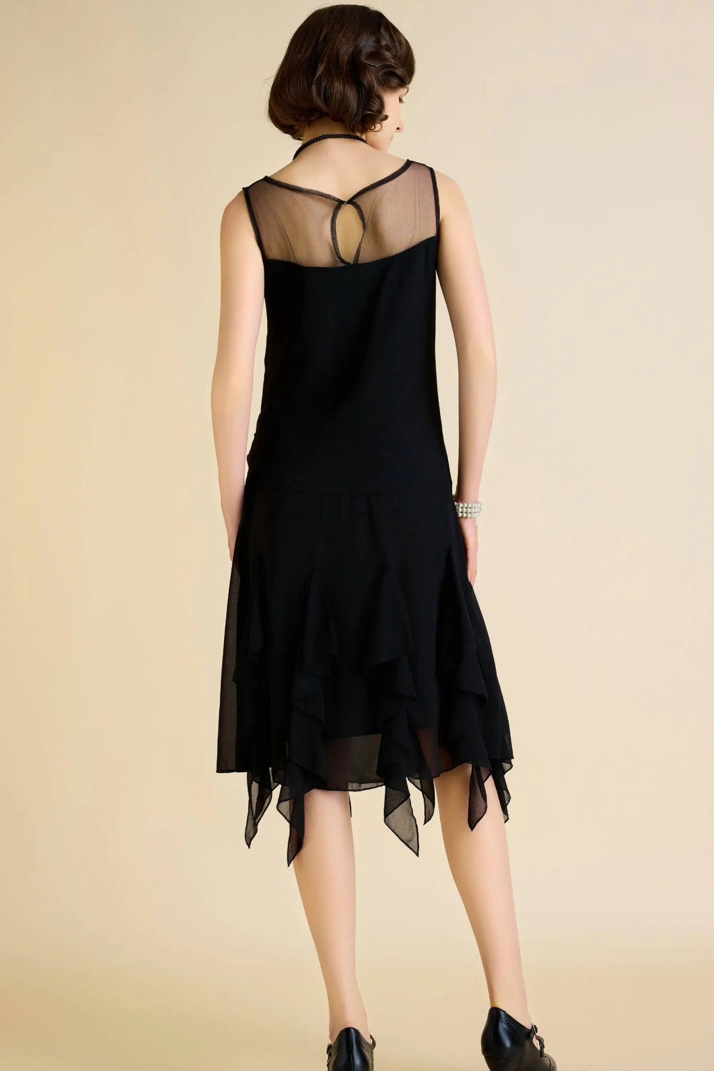 Women’s black sleeveless flapper dress with sheer décolletage and handkerchief hem