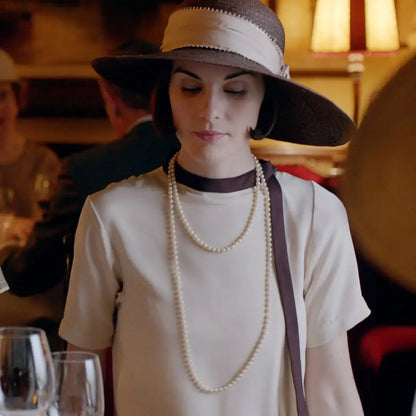 Woman in Downton Abbey replica dress with draped cascading ruffle and pearl necklaces