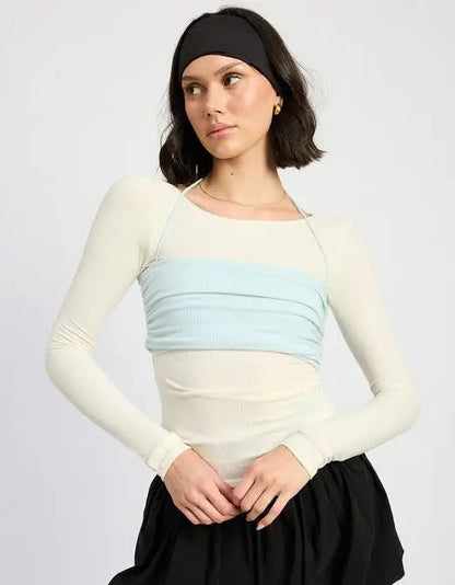 Woman wearing beige long sleeve top with light blue ruched bandeau and black skirt