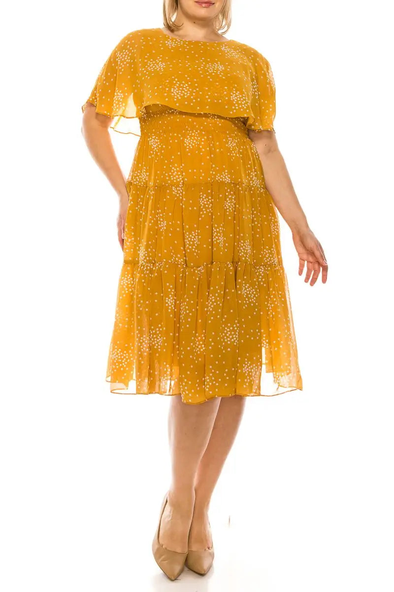 Woman in Maison Tara Golden Spice tiered midi dress with polka dots and flutter sleeves