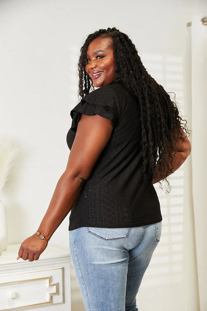 Black short-sleeved flutter sleeve blouse with silver embellishments paired with plus size denim jeans