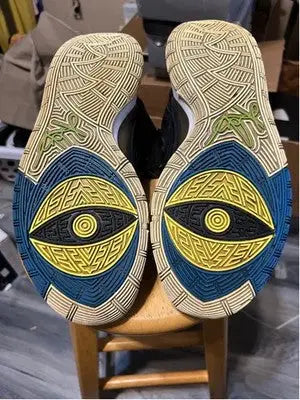 Soles of Nike Kyrie athletic shoes with prominent eye design in black and blue