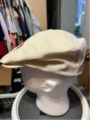 Off-white textured beret with red embellishment on mannequin head, ideal flat cap style