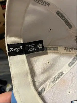 White men’s Zephyr UNC Tar Heels hat with black tag, size XL, made in Bangladesh, light blue accents