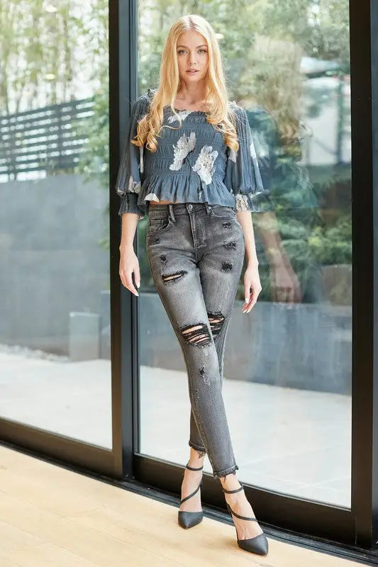 Mid rise skinny jeans with distressed detail, paired with a dark blue patterned blouse and black heels