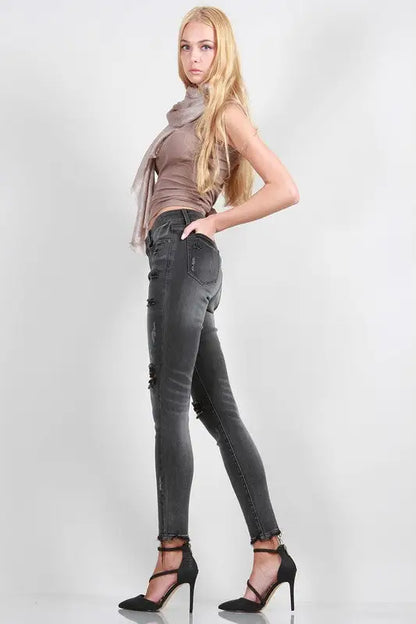 Young woman modeling distressed mid rise skinny jeans with taupe tank top and black heels