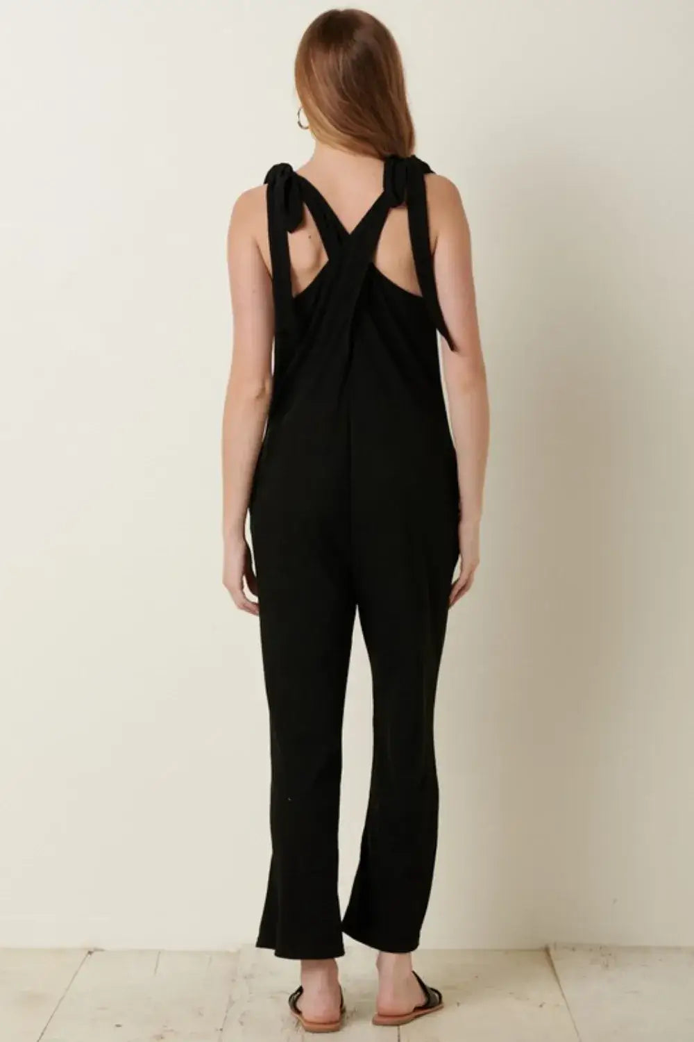 Black rib knit V-neck jumpsuit with crisscross back design and flared legs