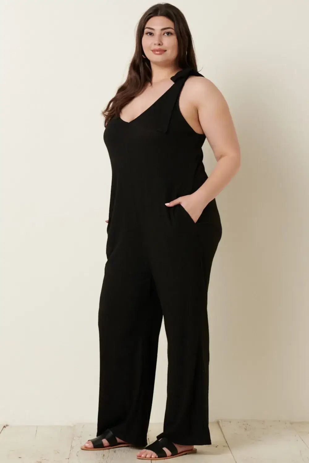 Black rib knit V-neck cross back jumpsuit with pockets paired with sandals