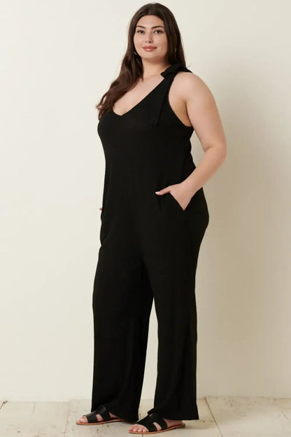 Black rib knit V-neck cross back jumpsuit with pockets paired with sandals