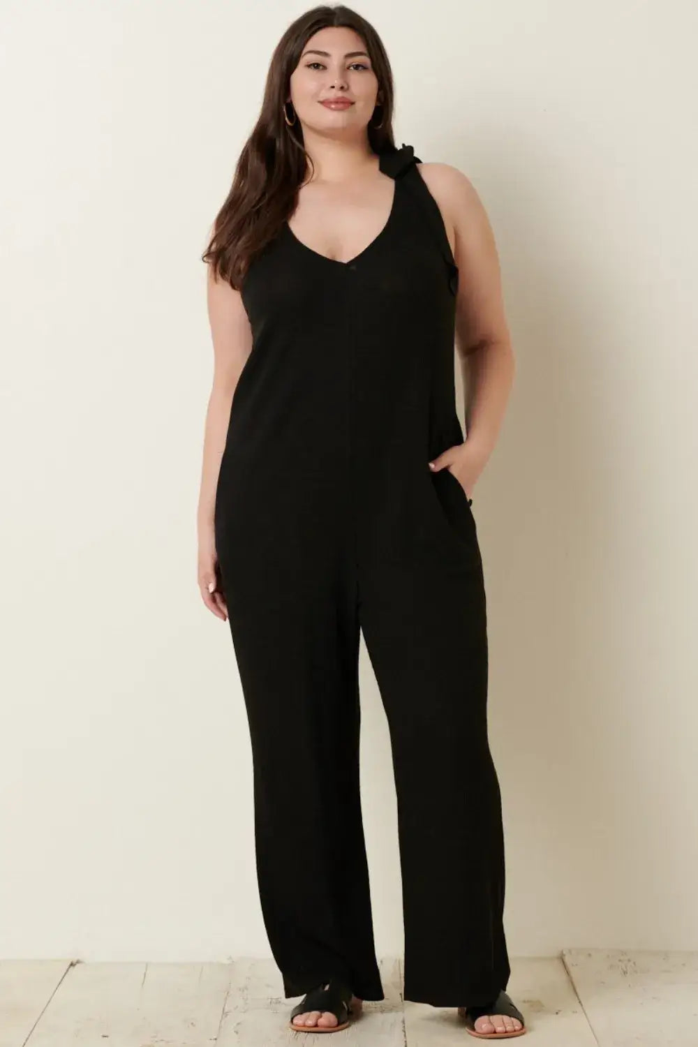 Black rib knit V-neck cross back jumpsuit with pockets and floral shoulder embellishment