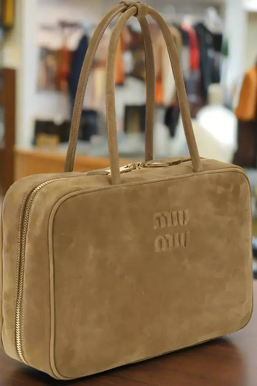 Miu Miu tan suede handbag with top handles and gold zipper showcasing Italian luxury