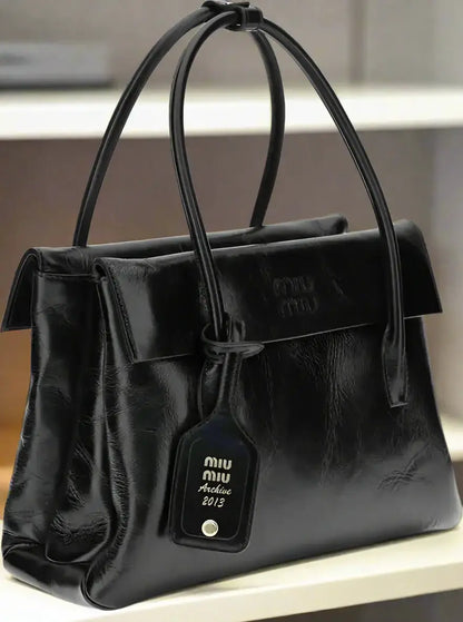Shiny black leather Miu Miu solitaire handbag with top handles and detachable tag