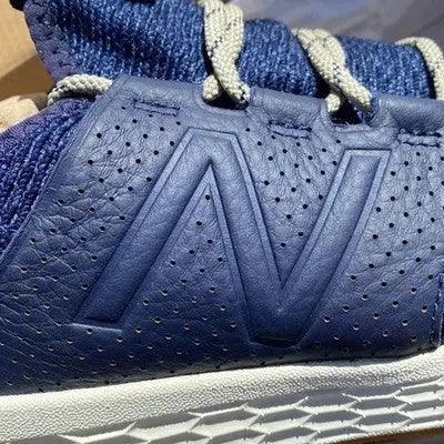 Dark blue perforated leather New Balance athletic sneakers with light laces and white sole