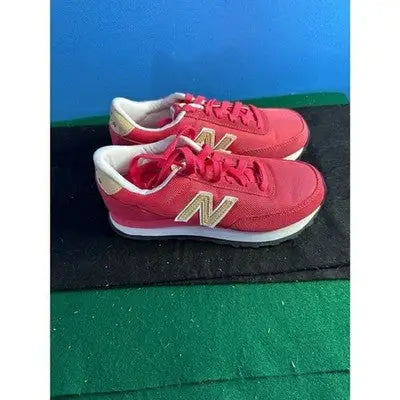 Pair of red New Balance low top sneakers with gold N logos for women size 5.5