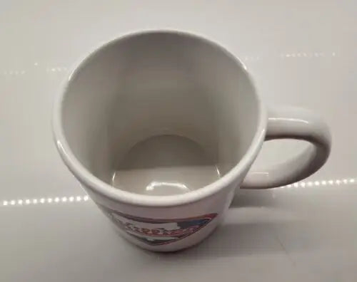 Empty white ceramic coffee mug featuring Philadelphia Phillies white bell logo design