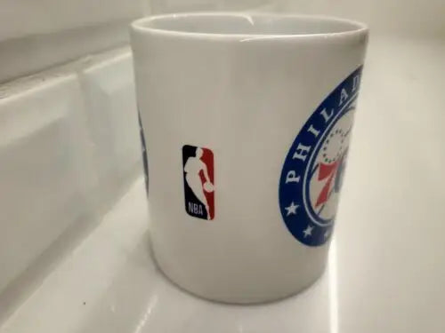 White ceramic coffee cup with NBA Philadelphia 76ers logos featuring NBA Philadelphia branding