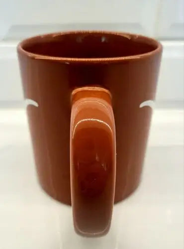 Brown ceramic coffee mug with handle featuring University of Texas Longhorns logo