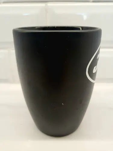 Black ceramic coffee mug featuring York Jets logo, perfect for NFL fans