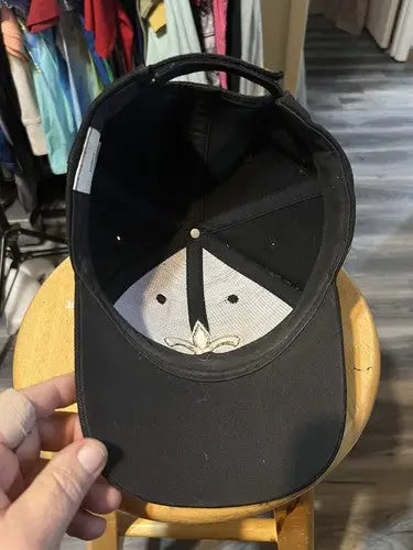 Black New Orleans Saints NFL hat with white underside and fleur-de-lis emblem