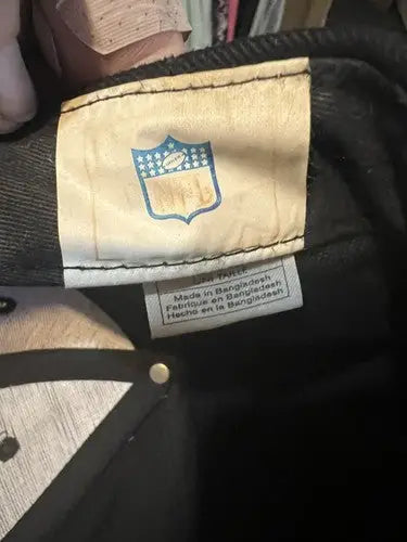 White clothing tag with NFL shield logo and Made in Bangladesh on New Orleans Saints NFL hat