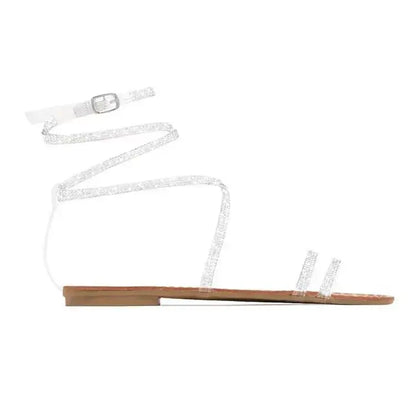 Clear strappy flat sandal with buckle closure and ankle wrap, perfect for decorating root