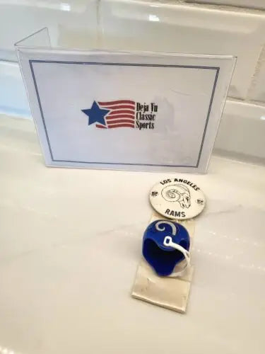 Vintage LA Rams memorabilia featuring a Rams pin, ribbon, and helmet for team spirit