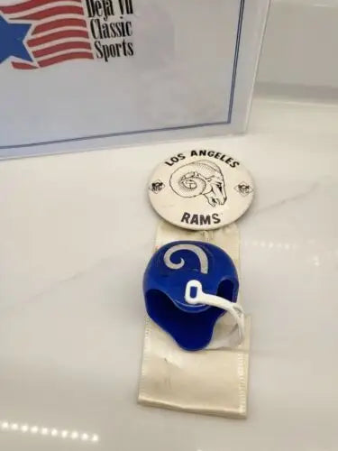 Vintage LA Rams memorabilia featuring a Rams pin, ribbon, and helmet for team spirit