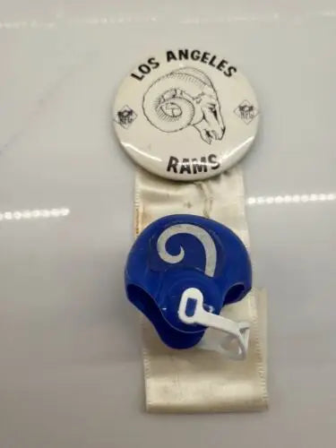 Vintage LA Rams memorabilia featuring a Rams pin, ribbon, and helmet for true team spirit