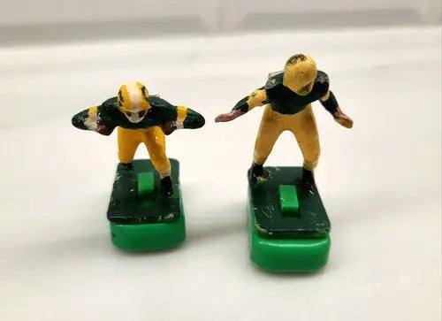 Two vintage electric football figurines of Green Bay Packers players with stands