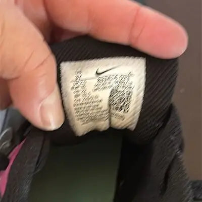 Hand holding Nike Air Max 833414-033 black youth running sneakers size tag