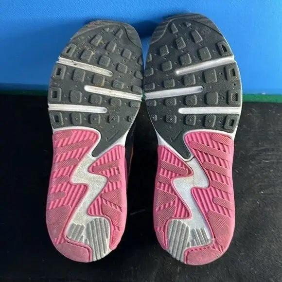 Bottoms of Nike Air Max Excee youth athletic sneakers with black, pink, and white soles