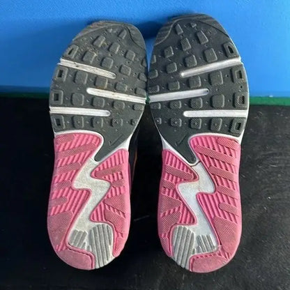 Bottoms of Nike Air Max Excee youth athletic sneakers with black, pink, and white soles