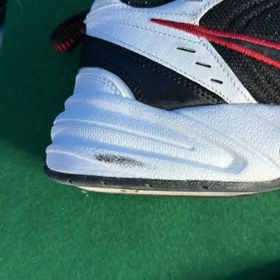 White and black Nike Air Max sneakers with red accents and a scuff mark on the sole
