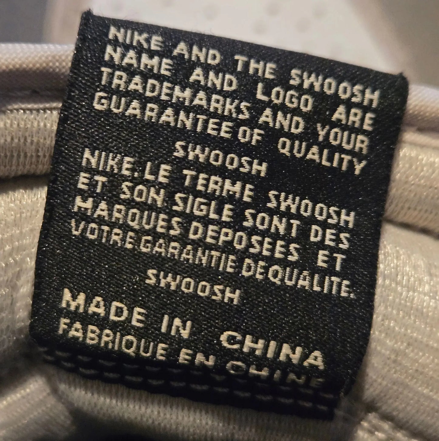 Black fabric Nike product tag with white text on Nike Jordan Air Leather Shoes with elephant print