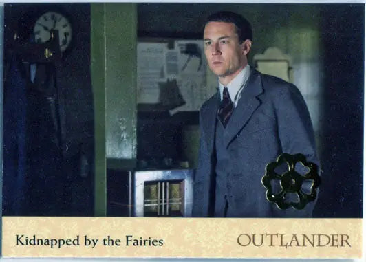 Man in gray suit in dim light showcases Gold Jacobite Seal Parallel Variant card