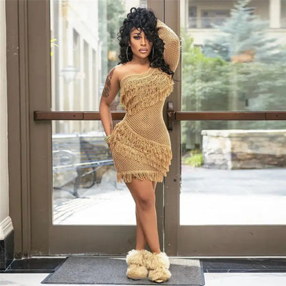Woman in beige inclined shoulder knit mini dress with fringe and fluffy boots