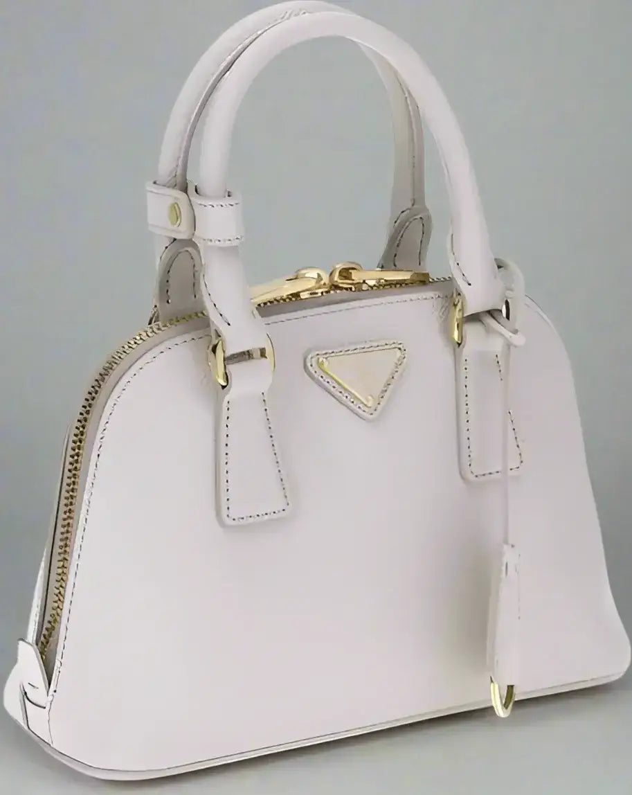 Light pink leather dome satchel with gold hardware, zip closure, and logo patch