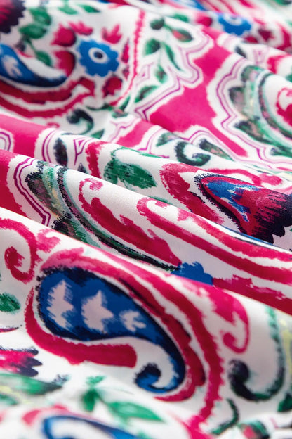 Vibrantly patterned printed tie neck short sleeve dress with paisley and floral motifs
