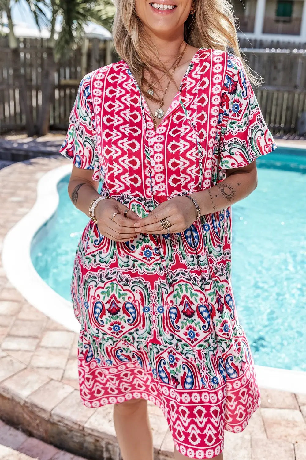 Woman wearing a printed tie neck short sleeve dress with vibrant bohemian pattern