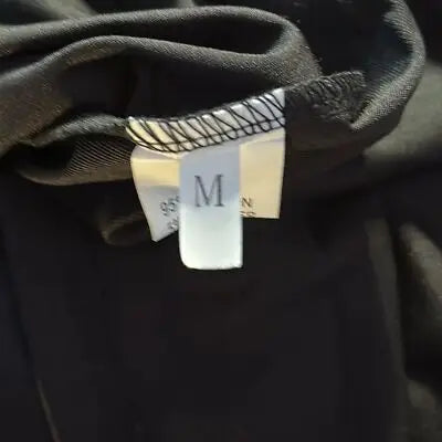 Black fabric garment with white care label showing size medium and 95 percent material content