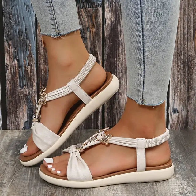 Roman style flat sandals with butterfly accents and elastic ankle straps for women