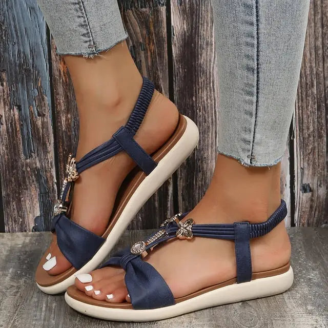 Roman style flat sandals with blue straps, white soles, and decorative embellishments