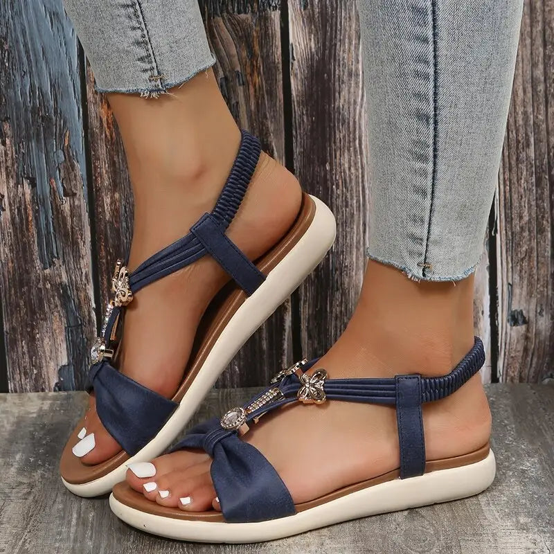Women’s navy blue Roman style flat sandals with butterfly embellishments and elastic straps