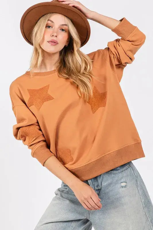 Rust-colored SAGE + FIG star patch long sleeve sweatshirt with ribbed cuffs and soft cotton blend