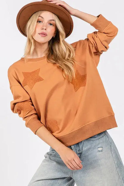 Rust-colored SAGE + FIG star patch long sleeve sweatshirt with ribbed cuffs and soft cotton blend